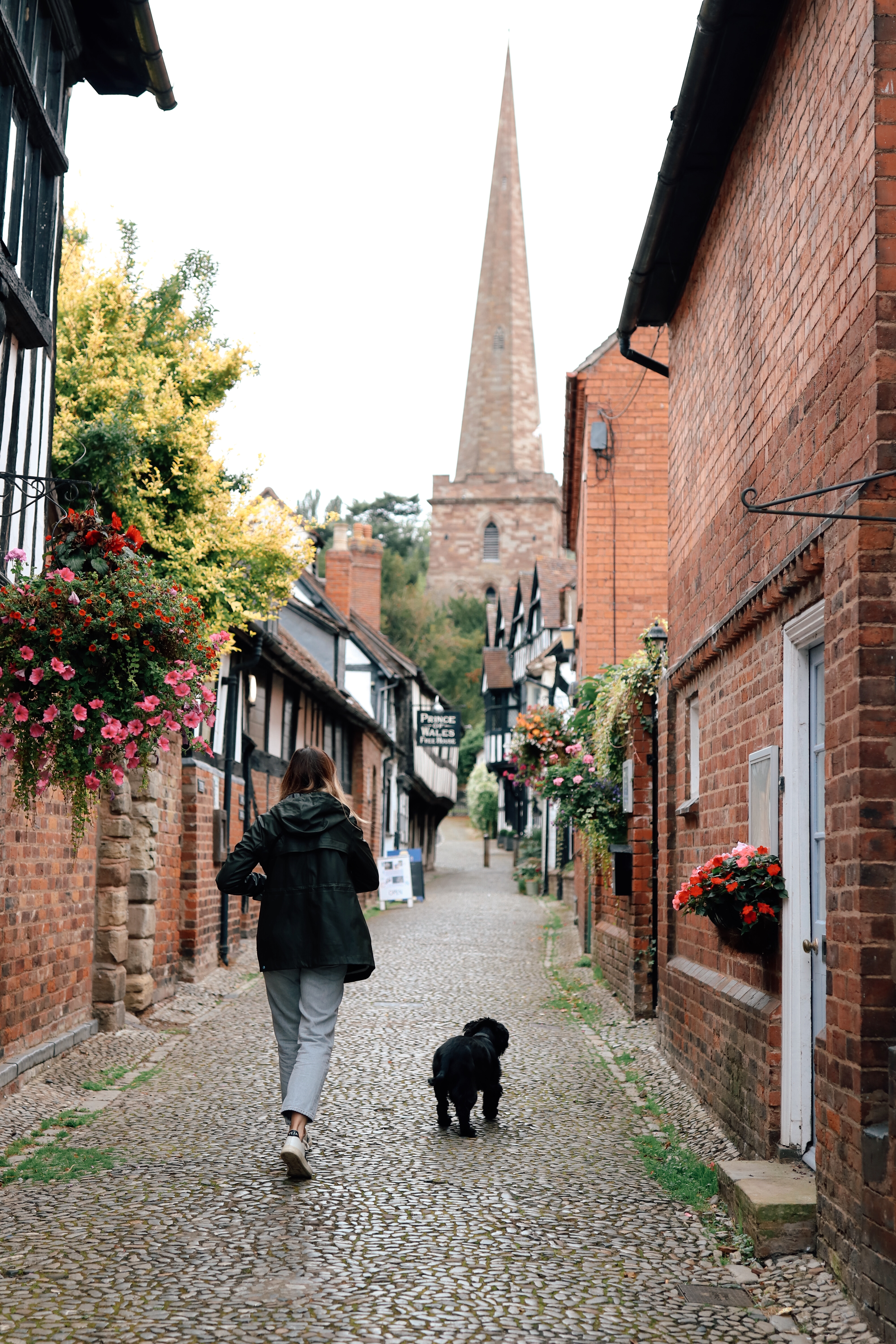 Women strolling up cobbled church lane with her dog