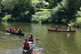 Pairs of people canoe the River Wye in 3 boats