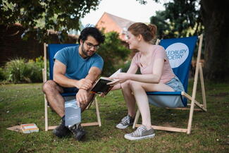 couple sat on deckchairs reading a book at Ledbury Poetry festival