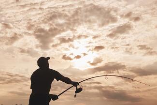 Silhouette of man fishing over lake