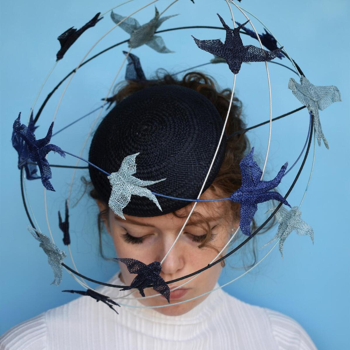 Woman against blue wall with artwork hat