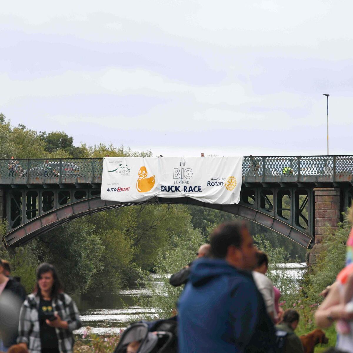 large duck race banner hanging from the side of a bridge