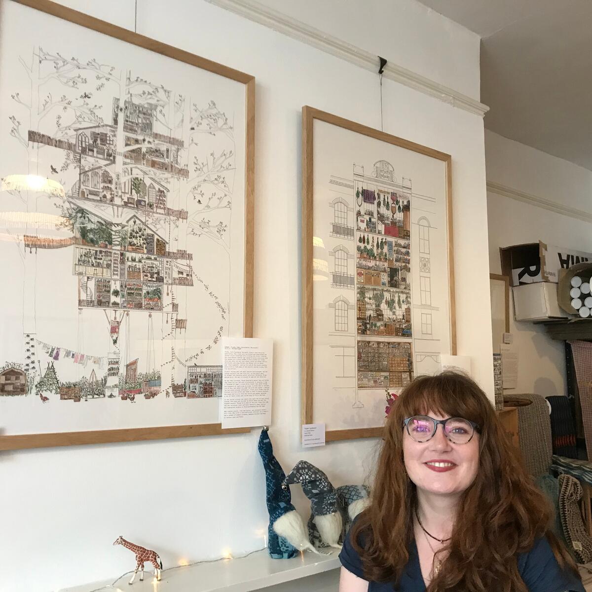 lady with glasses in front of framed artwork on the wall