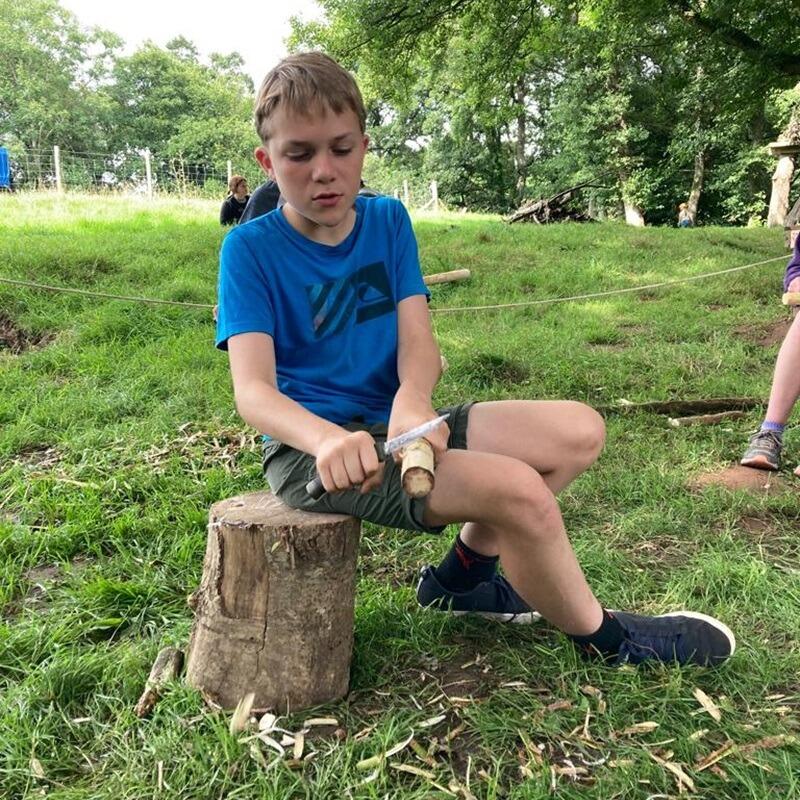 adolescent child whittling wood 