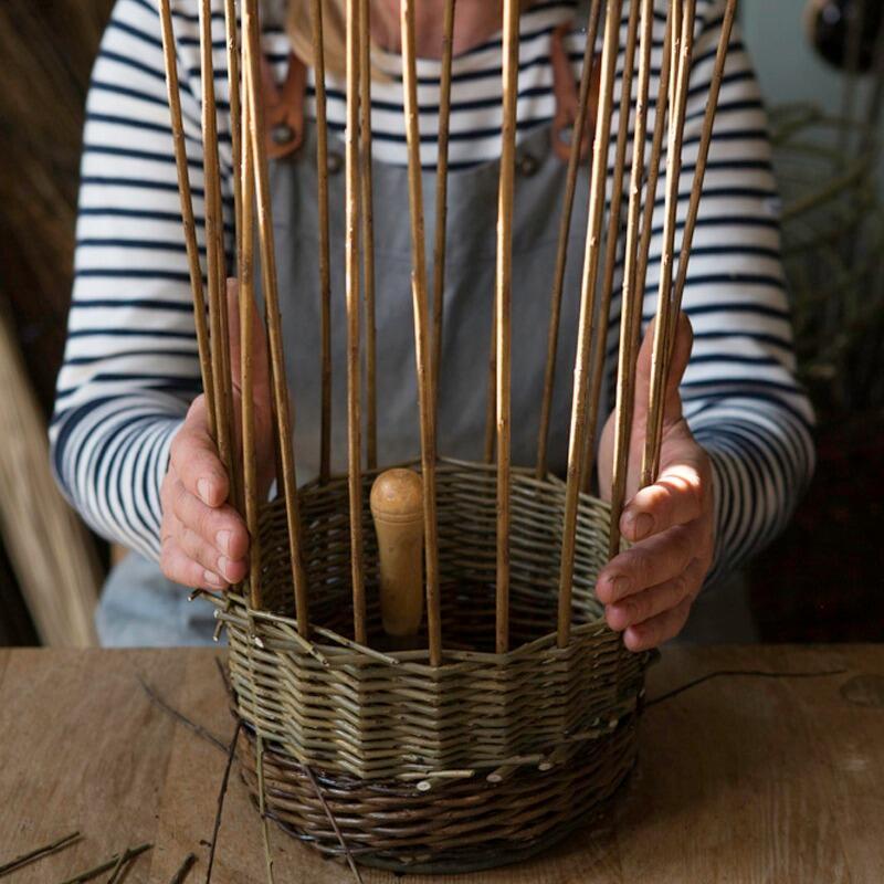 Person holding woven willow backet in the process of being made