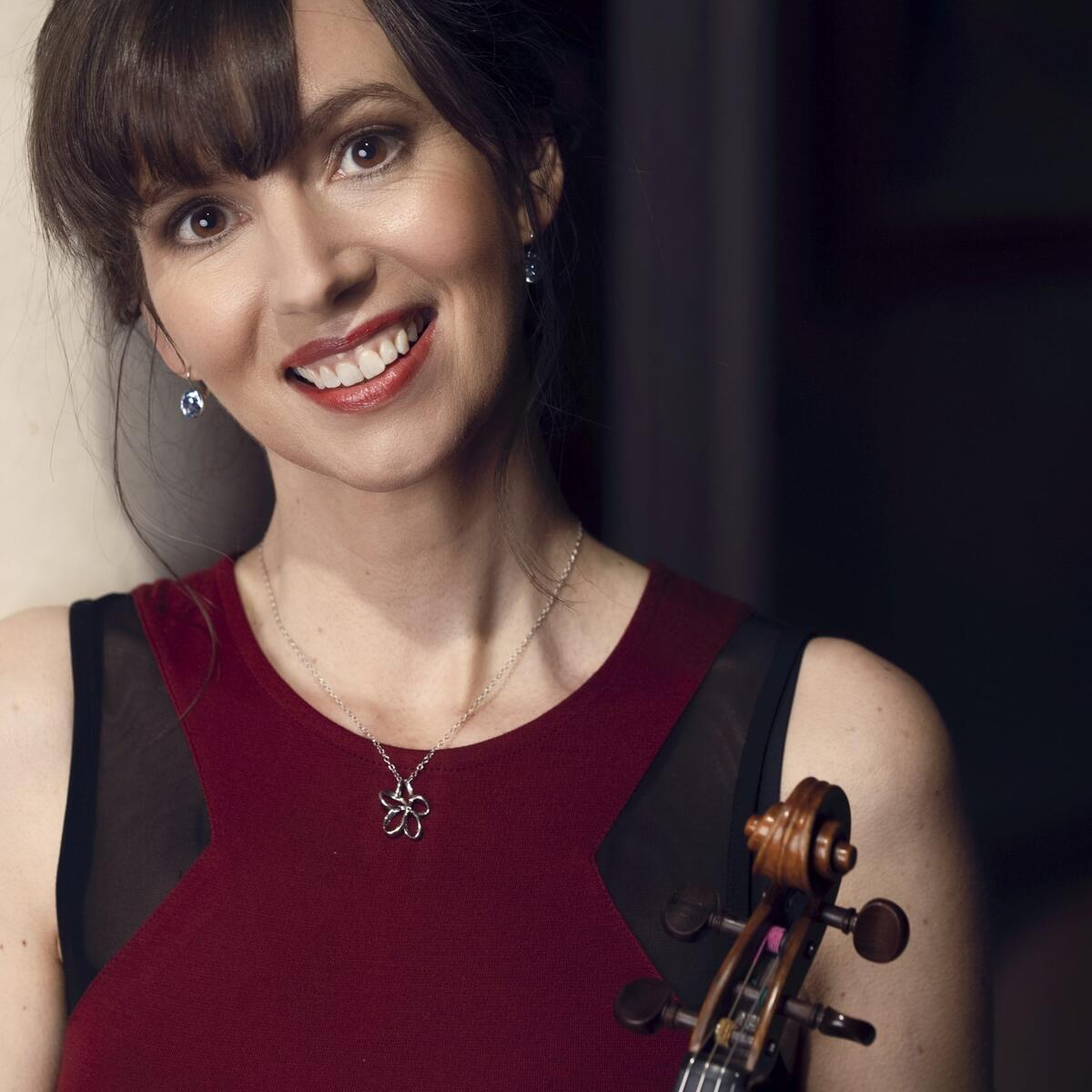 Sara Trickey smiling holding a violin