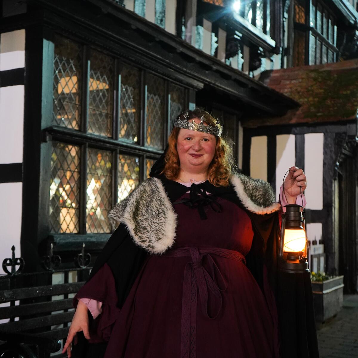 Person dresses in costume and crown holding a lantern