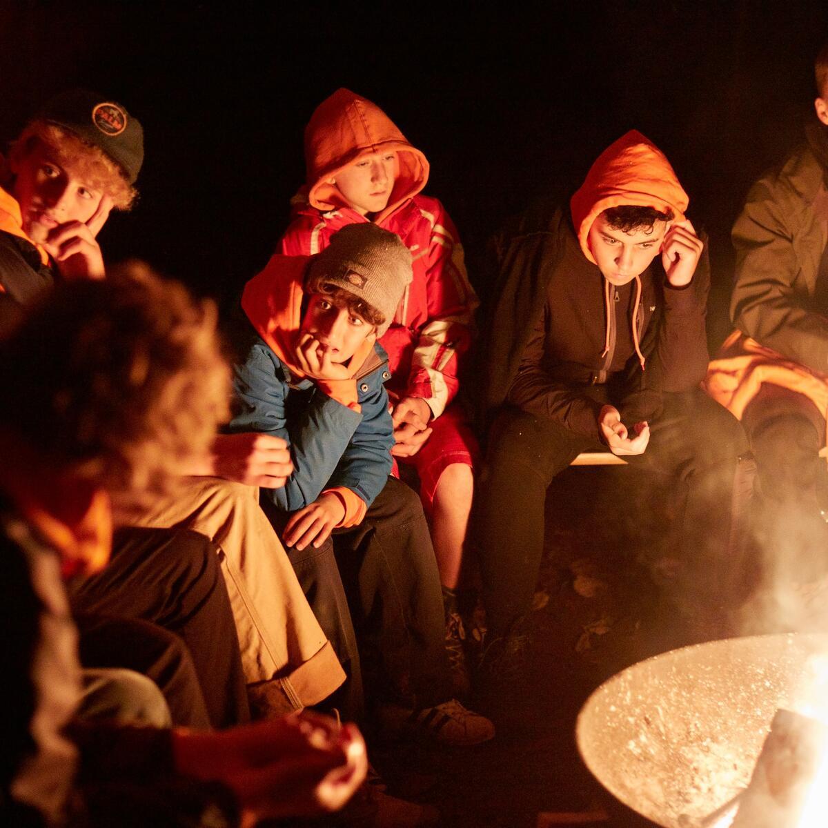 People sat around a firepit talking in the evening