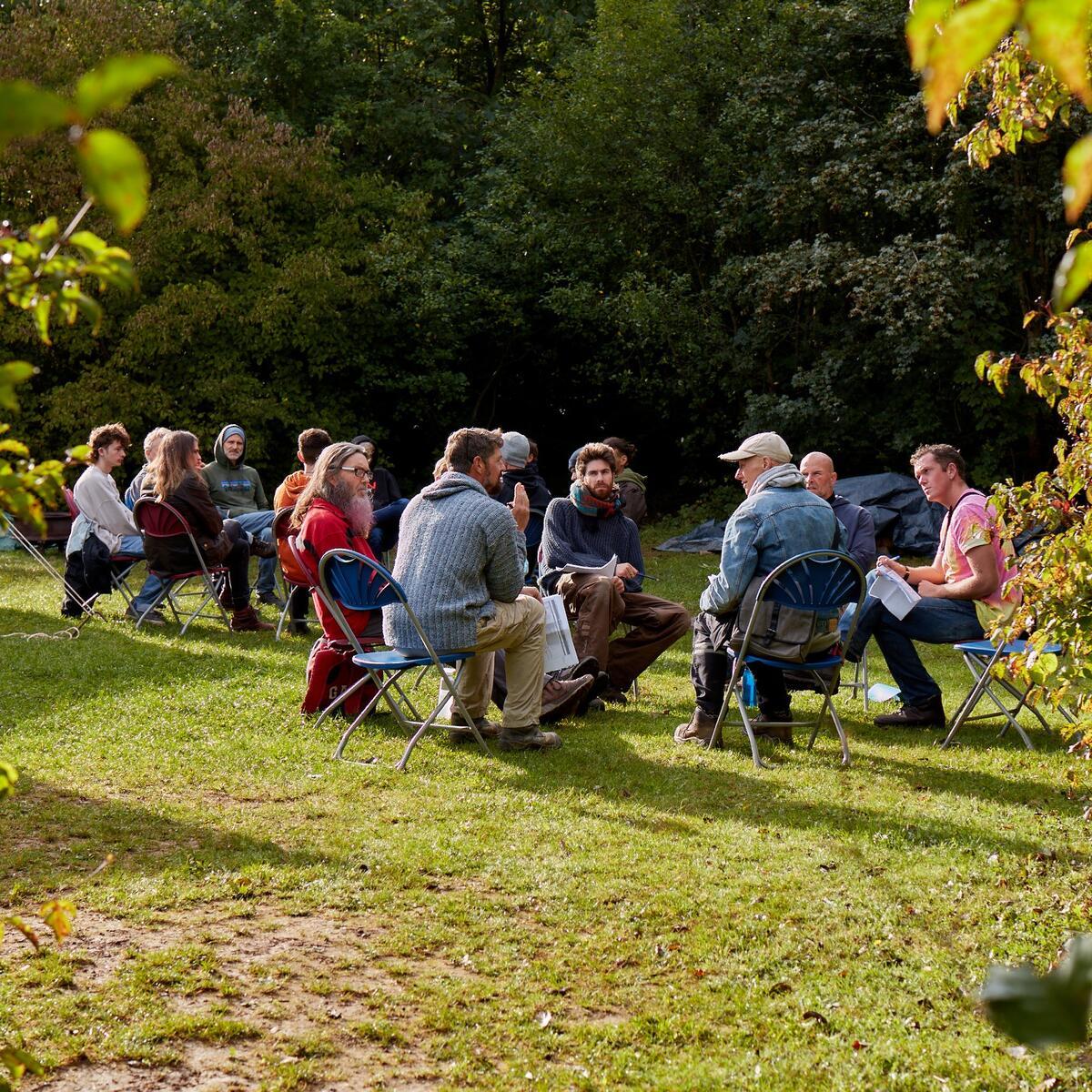 A group of young people sat on chairs on a larn talking