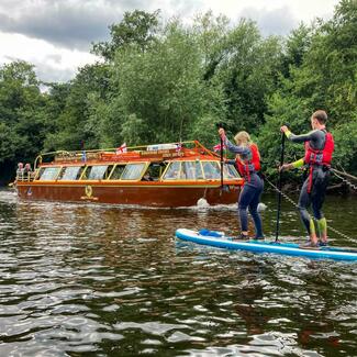 people paddle boarding next to boat on river