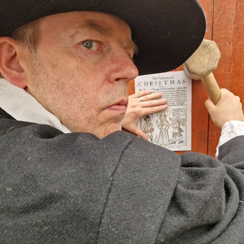 Puritan man putting up poster to say Christmas is banned