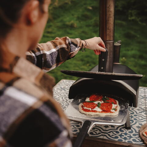 making a pizza in the outdoor pizza oven