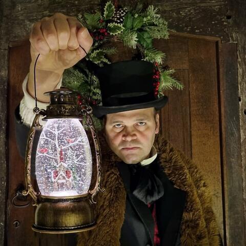 A man in a brown coat, white shirt and black waistcoat with black top hat holding a snow globe lantern