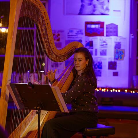 Female playing a large harp in dimmed light