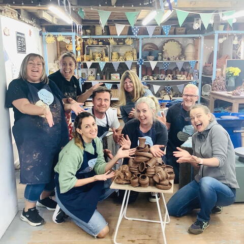 A group of pottery course attendees with their handmade pots