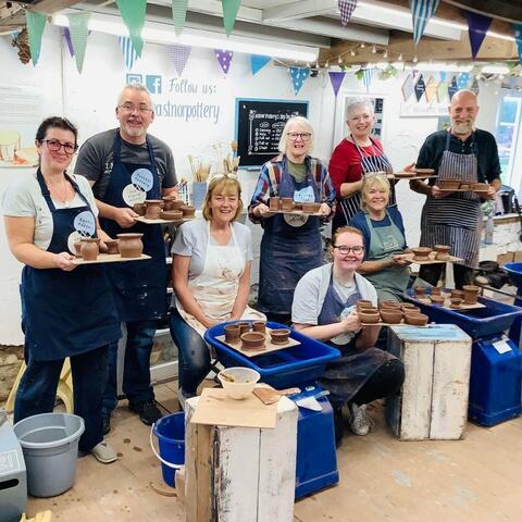 Group of pottery class attendees with their pots 