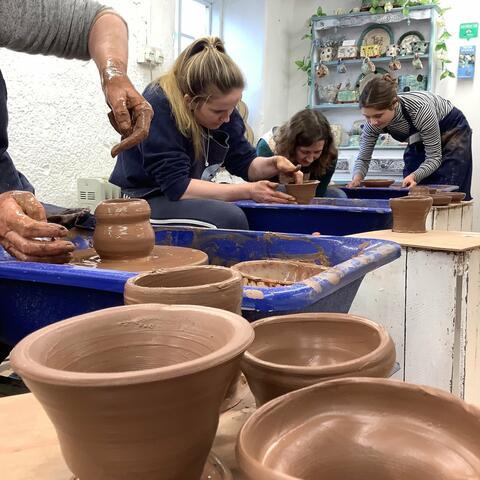 thrown clay pots with person laughing in background