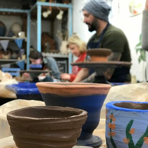 thrown clay pots with person laughing in background