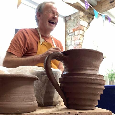 thrown clay pots with person laughing in background