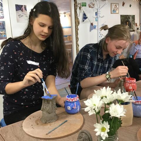 Young people glazing hand made clay pots