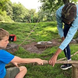 child sawing branches with help from adult