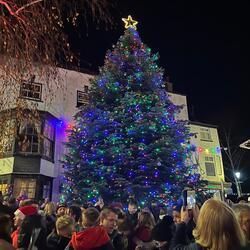 large decorated Christmas tree in town square with crowds