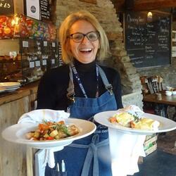 Person smiling and serving a cooked breakfast