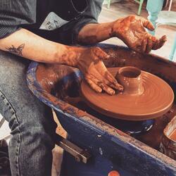 hands on a clay pot on a potter's wheel